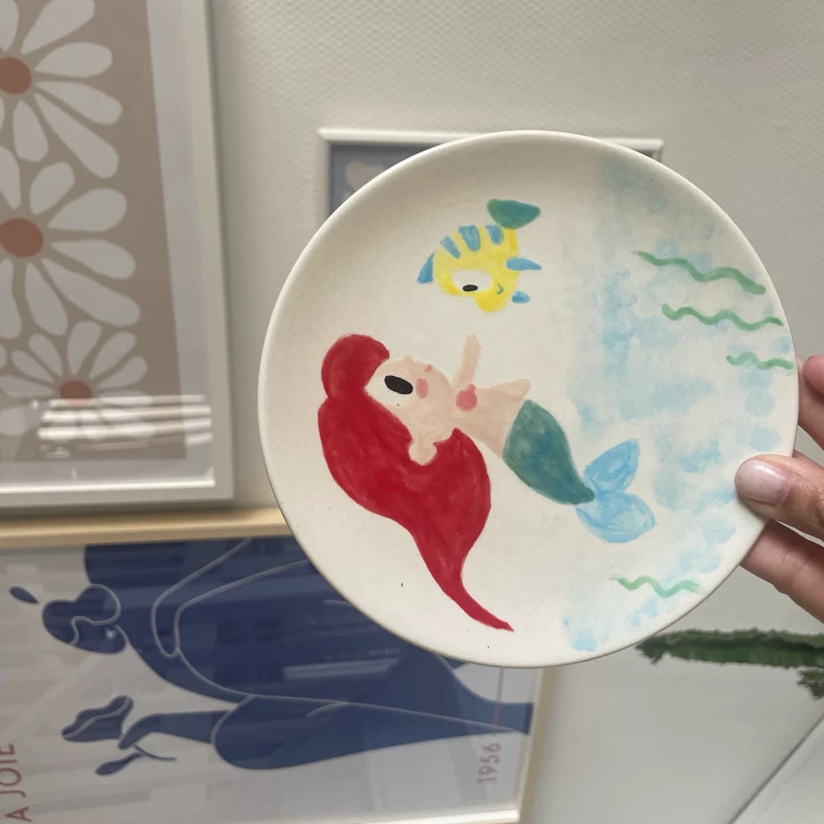 Assiette tenue à la main peinte d’un personnage de conte sous l’eau et d’un petit poisson