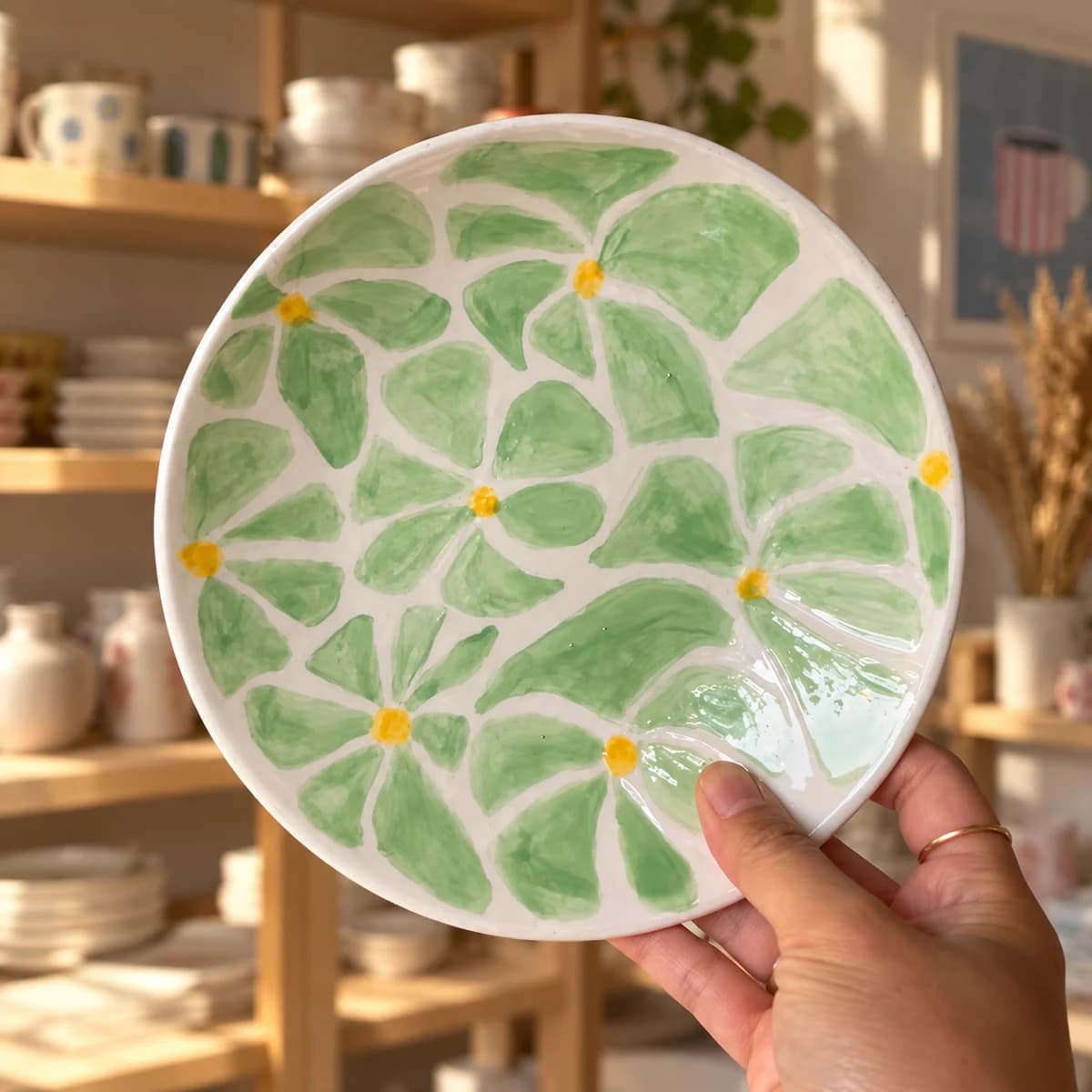 Assiette peinte de grandes feuilles vert clair avec de petits centres jaunes