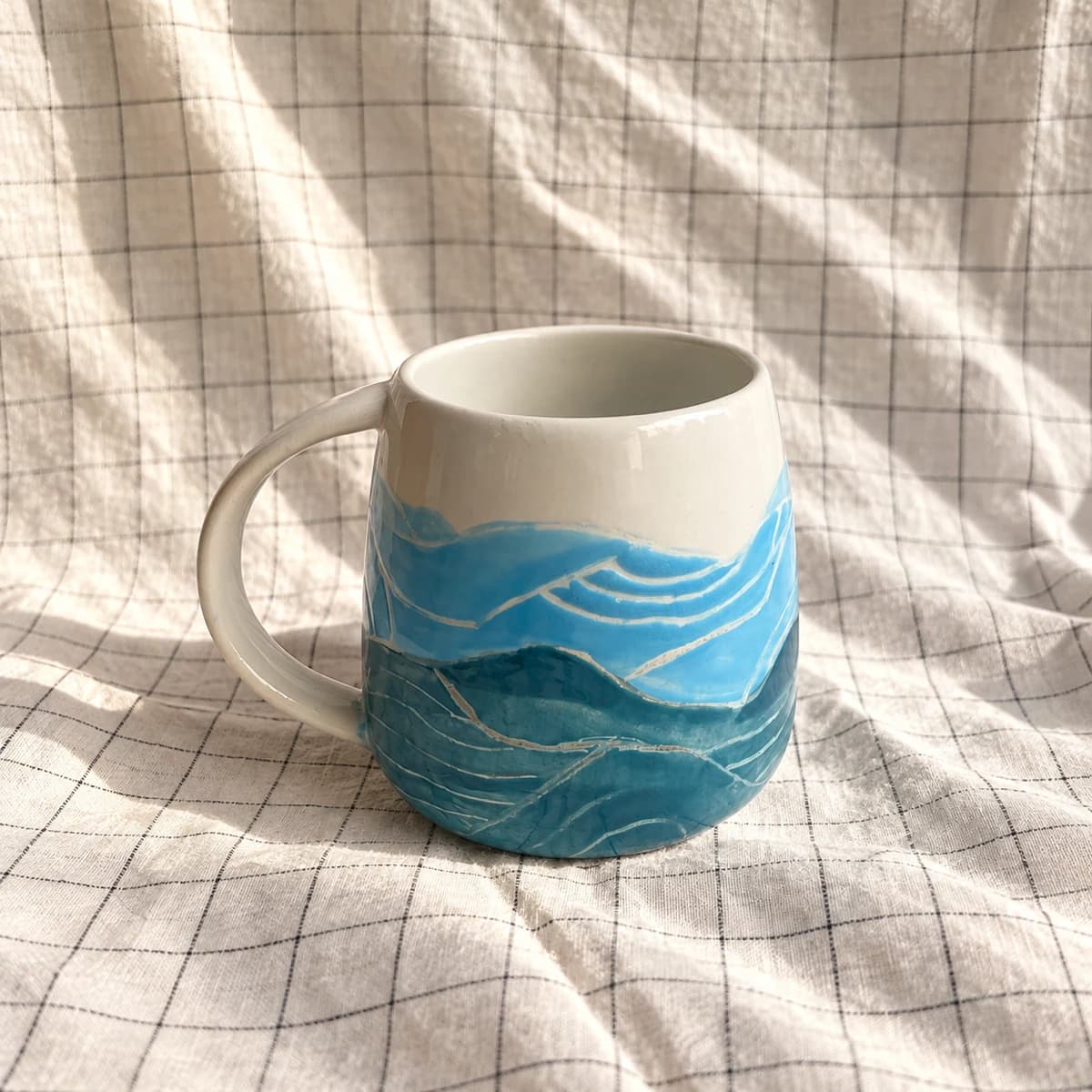Mug blanc peint de vagues dans plusieurs nuances de bleu