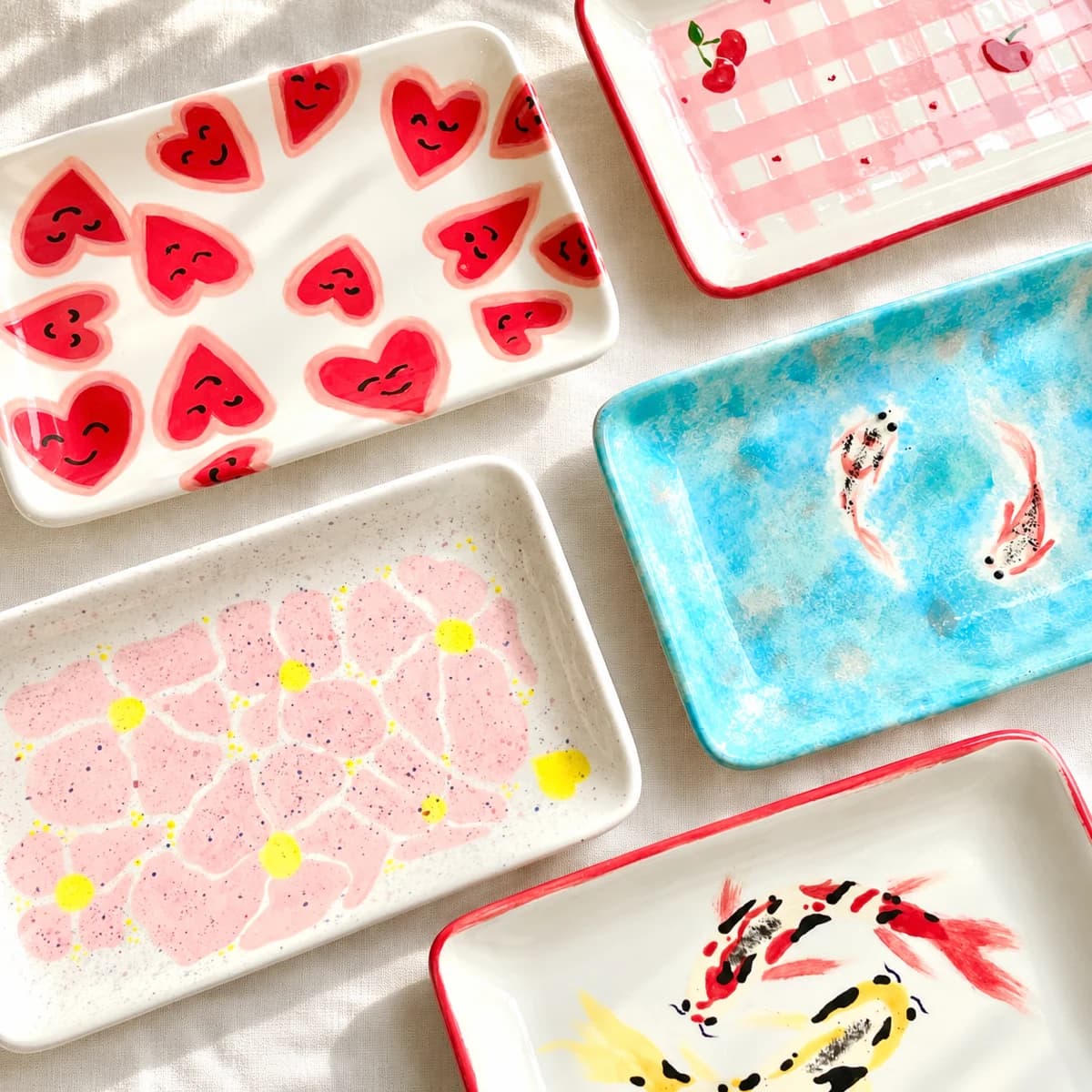 Composition de plateaux en céramique peints de cœurs, fleurs et poissons